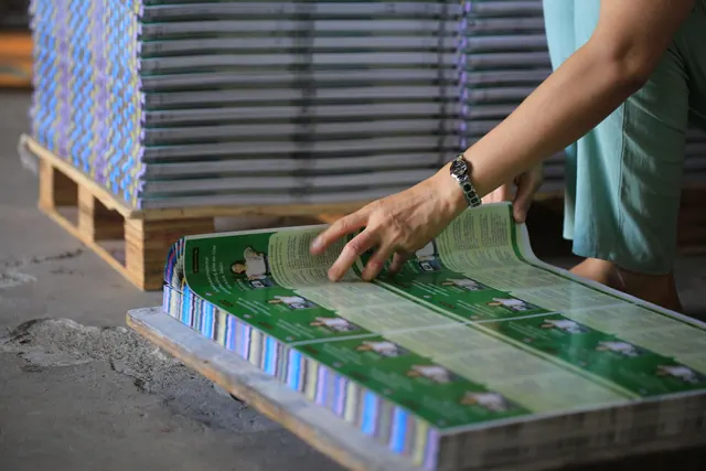 A person organizes stacks of printed publications in an industrial warehouse setting. Billboard advertising costs by state: what budgets should assume