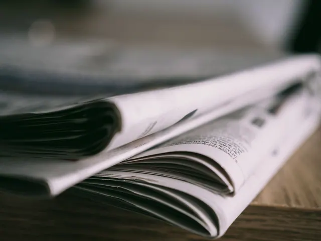 Stack of folded newspapers on a wooden table with a focus on printed pages. What does a local newspaper ad actually cost?