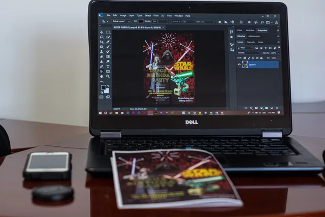 A laptop displaying Star Wars party invitation design in a workspace setting. Marketing collateral tools compared on rights, proofs and exports