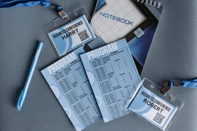 Flat lay of business conference materials including name tags, program, notebook, and pen. Trade show lead capture: six tests to run before the show