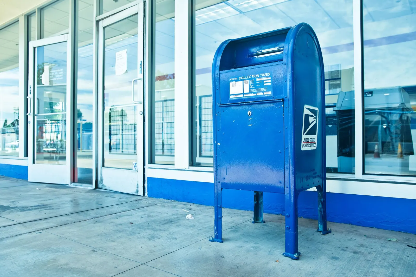 USPS blue mailbox against a post office facade in Los Angeles, CA. A practical guide to USPS Every Door Direct Mail rates